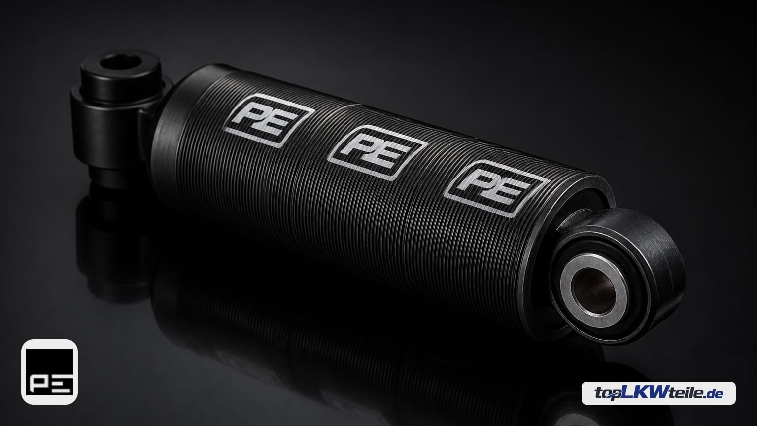 PE Automotive Dämpfer, Fahrerhauslagerung auf dunkler, reflektierender Fläche – zylindrischer schwarzer Dämpfer mit zwei Gummiaugen und auffälligem PE-Logo.